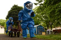 Airmen from the 374th Civil Engineer Squadron and the 374th Aerospace Medicine Squadron move toward to the scene of a mock chemical threat, May 6, 2015, at Yokota Air Base, Japan. According to the training scenario, responders were called to investigate after a simulated resident was discovered passed out in base housing. (U.S. Air Force photo by Airman 1st Class Elizabeth Baker/Released)