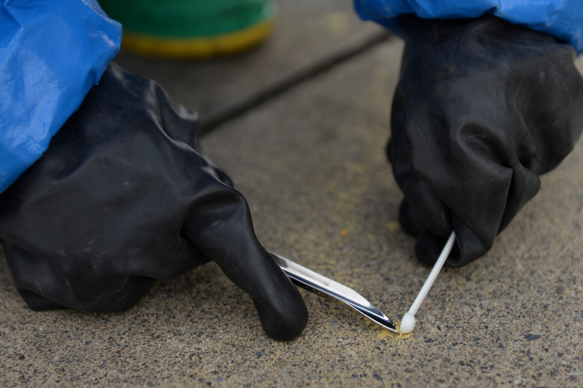 An Airman from the 374th Civil Engineer Squadron collects a sample of a powder, May 7, 2015, at Yokota Air Base, Japan. The powder was discovered beside a mock body during an emergency response training exercise. (U.S. Air Force photo by Airman 1st Class Elizabeth Baker/Released)