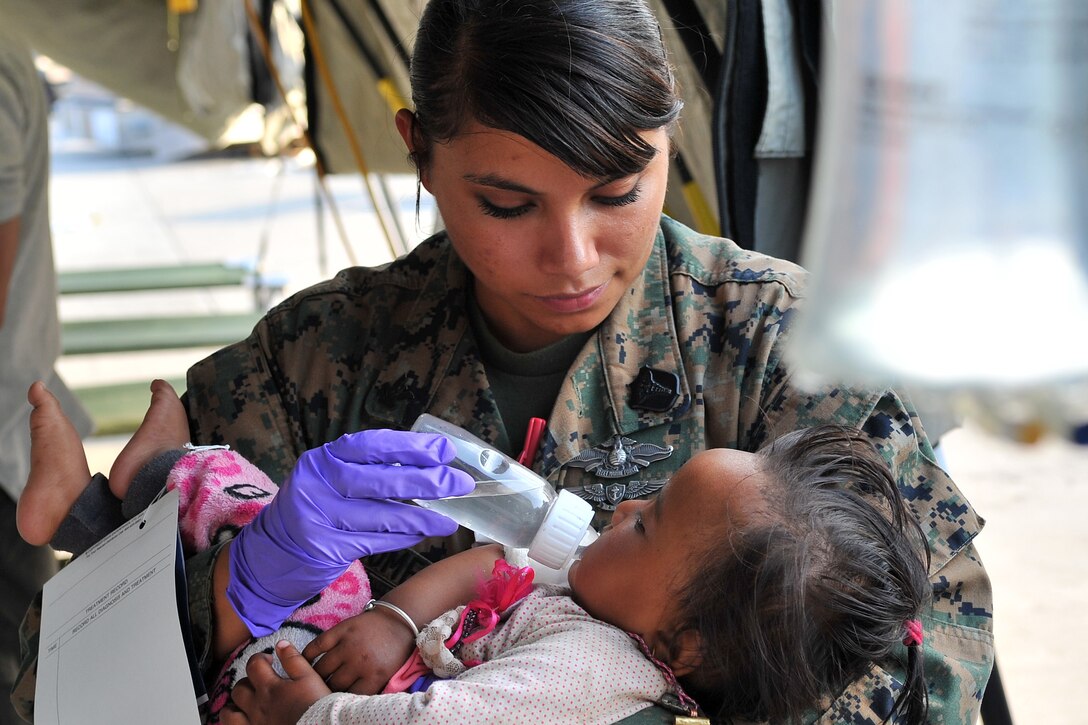 U.S. Navy Petty Officer 2nd Class Jessica Gomez-Hickman comforts an infant earthquake victim at the Tribhuvan International Airport in Kathmandu, Nepal, May 12, 2015. Gomez-Hickman is a hospital corpsman assigned to Marine Light Attack Helicopter Squadron 469.