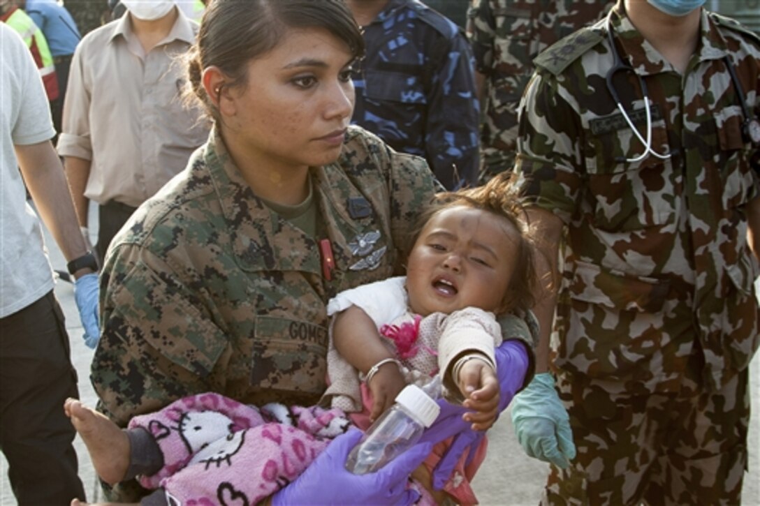 U.S. Navy Petty Officer 2nd Class Jessica Gomez-Hickman holds a young earthquake victim before placing her in an ambulance at a medical triage area at Tribhuvan International Airport in Kathmandu, Nepal, May 12, 2015. 