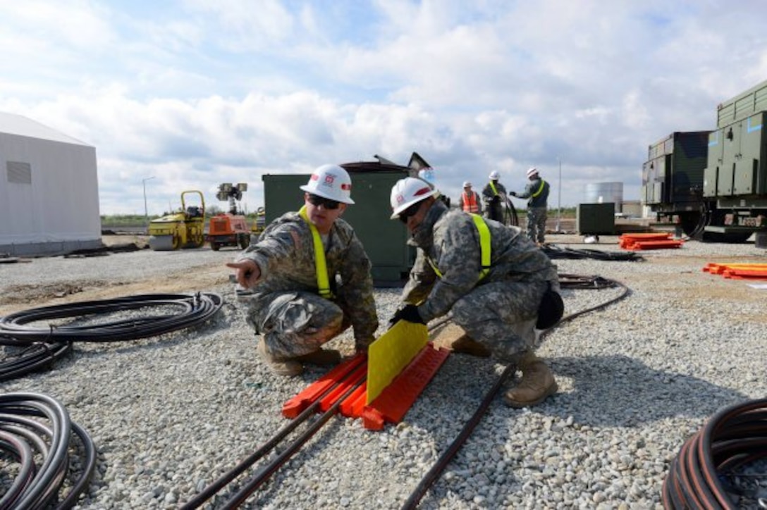 Sgt. Zackery Slater, left, from Warrenton, Va., and Sgt. Win Htun, from New York, route power cables at Naval Support Facility Deveselu, Romania, April 19, 2015. The Soldiers are assigned to 249th Engineer Battalion from Fort Belvoir, Va., and helped...