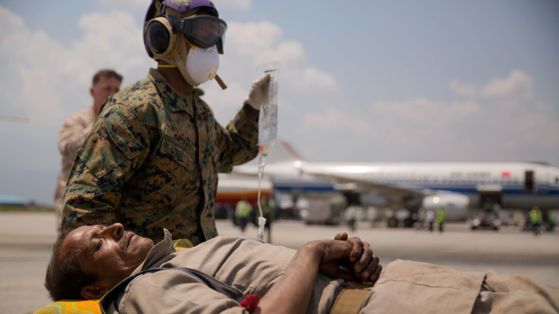 A U.S. Marine helps carry a Nepalese man to a triage at the Tribhuvan International Airport in Kathmandu, Nepal, May 13. Joint Task Force 505 service members are in Nepal conducting earthquake recovery operations as part of Operation Sahayogi Haat. A 7.3 magnitude earthquake shook the country May 12, nearly two weeks after a larger earthquake struck April 25. 