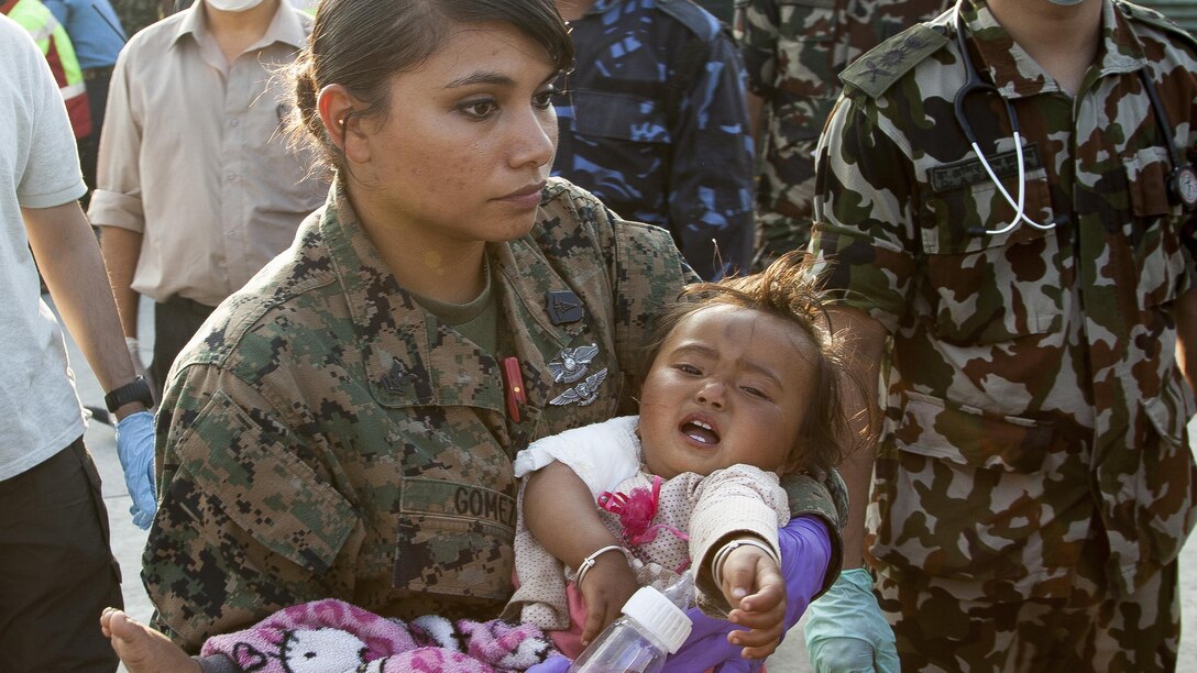 U.S. Navy Petty Officer 2nd Class Jessica Gomez-Hickman, from Joint Task Force 505 and Carey, Idaho native, holds a young earthquake victim before loading her into an ambulance at a medical triage area at Tribhuvan International Airport, Kathmandu, Nepal, after a 7.3 magnitude earthquake struck the country, May 12. Joint Task Force 505 along with other multinational forces and humanitarian relief organizations are currently in the Nepal providing aid after a 7.8 magnitude earthquake struck the country, April 25. At Nepal’s request the U.S. government ordered JTF 505 to provide unique capabilities to assist Nepal. (U.S. Marine Corps photo by Gunnery Sgt. Ricardo Morales/Released)