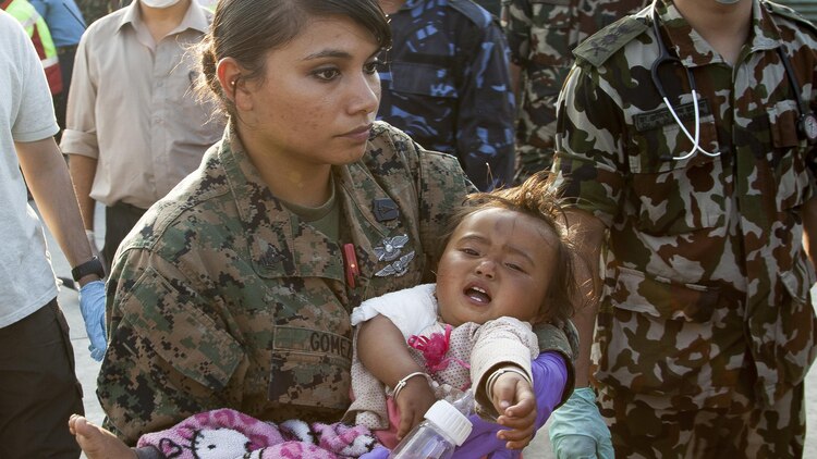 U.S. Navy Petty Officer 2nd Class Jessica Gomez-Hickman, from Joint Task Force 505 and Carey, Idaho native, holds a young earthquake victim before loading her into an ambulance at a medical triage area at Tribhuvan International Airport, Kathmandu, Nepal, after a 7.3 magnitude earthquake struck the country, May 12. Joint Task Force 505 along with other multinational forces and humanitarian relief organizations are currently in the Nepal providing aid after a 7.8 magnitude earthquake struck the country, April 25. At Nepal’s request the U.S. government ordered JTF 505 to provide unique capabilities to assist Nepal. (U.S. Marine Corps photo by Gunnery Sgt. Ricardo Morales/Released)