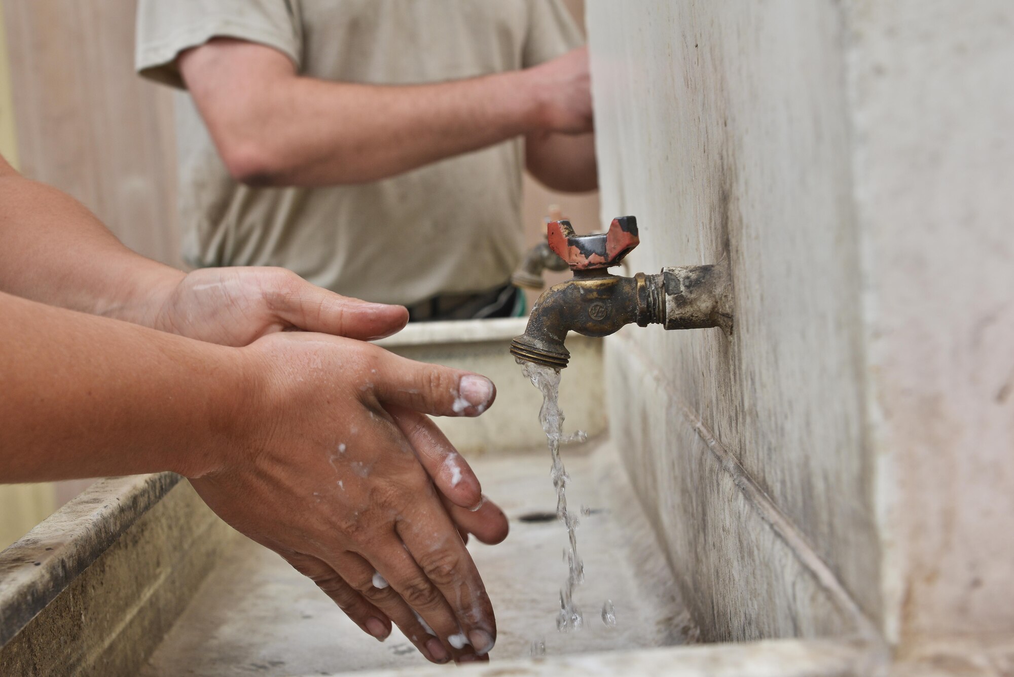 Aerospace Ground Equipment airmen wash their hands removing dirt, oil and chemicals that they have come in contact with to maintain sanitation and control the spread of germs or illnesses during shift breaks at Al Udeid Air Base, Qatar. Shift-breaks and hours vary depending on the work to rest ration in heat stress conditions. During the summer months deployed airmen sometimes conduct their mission in wet-bulb globe temperature index of black flag, which is recommended to have a 15 minute work with a 45 minute rest schedule and a “buddy system” to keep their wingman safe.  (U.S. Air Force photo by Staff Sgt. Alexandre Montes)  