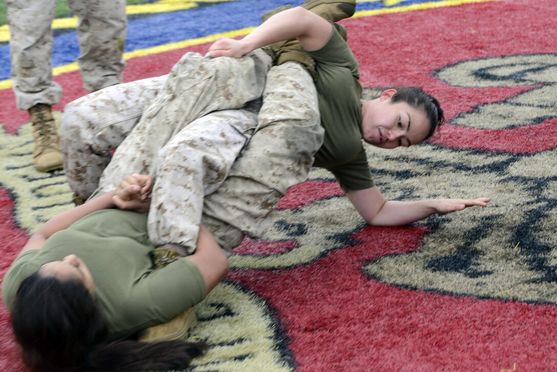 Sgt. Linda Valencia, Service team, top, grapples with Pvt. Lindsey Guevara, Headquarters team, during the Marine Corps Martial Arts Program Gauntlet at Butler Stadium on May 1. Headquarters team won the overall event. 