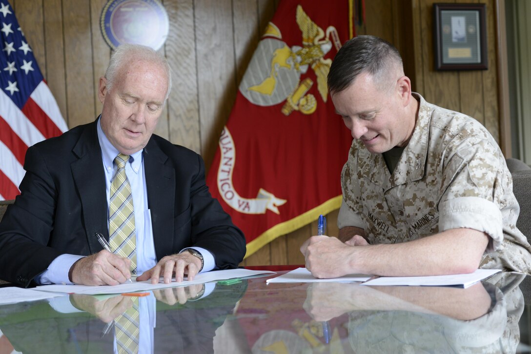 Col. David Maxwell, base commander, Marine Corps Base Quantico, right, signs a Memorandum of Agreement with Mark Gibb, director of the Northern Virginia Regional Commission, in an effort to provide and facilitate existing NVRC commuter services to Marine Corps Installations National Capital Region - Marine Corps Base Quantico personnel. The overall goal of the MOA is to enhance the Transportation Demand Management program.