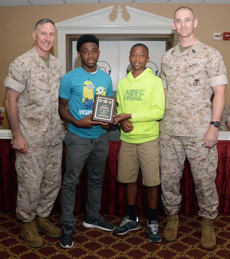 Col. Don Davis, commanding officer, Marine Corps Logistics Base Albany, and Master Sgt. William Tolleson, Marine Corps Logistics Command, present an award to students from a local school during the Mentors in Action luncheon held May 14 at Town and Country Restaurant’s Grand Ballroom.