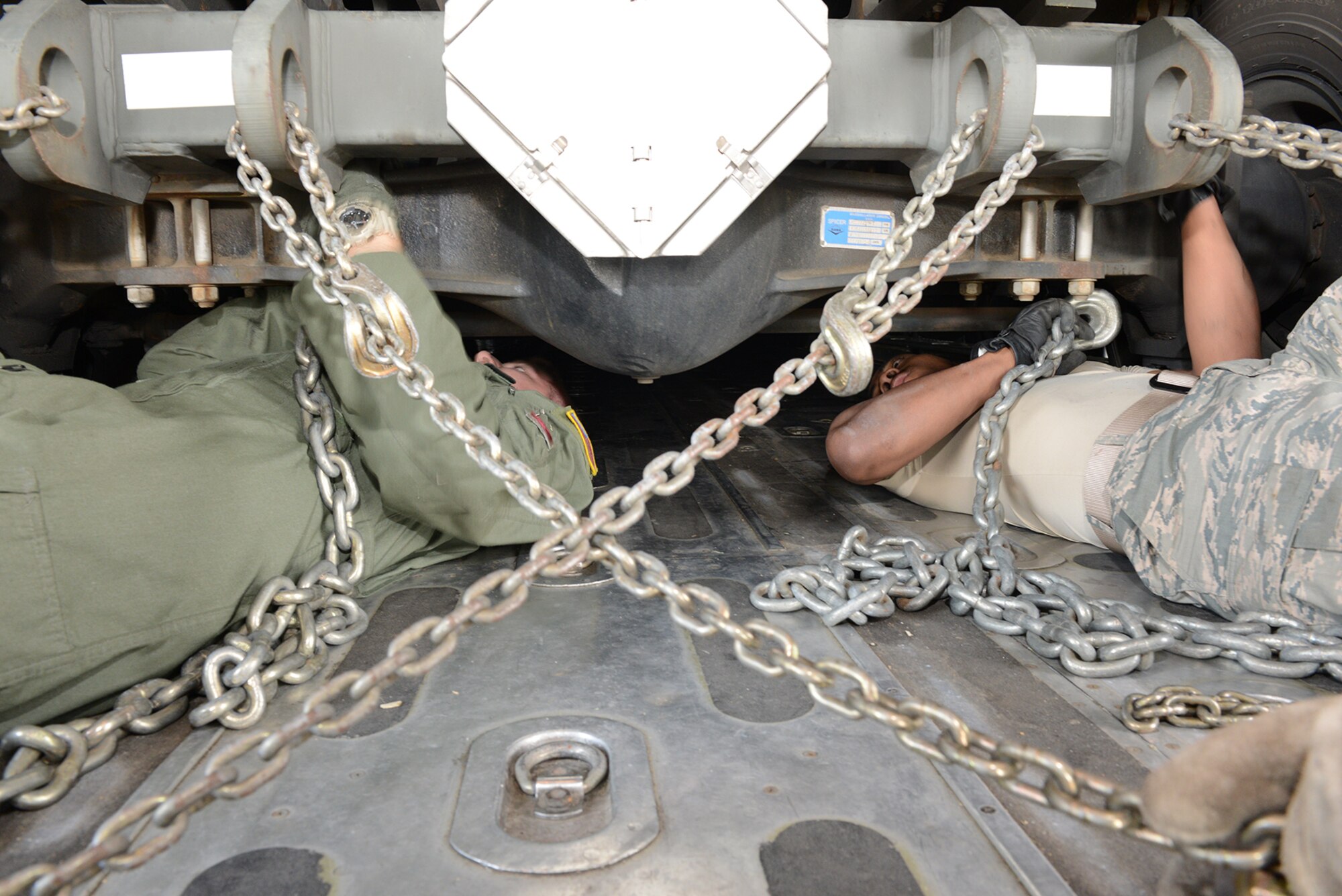 Airmen from the 374th Logistics Readiness Squadron and 36th Airlift Squadron attach chains to a K-loader May 14, 2015, at Yokota Air Base, Japan. The K-loader was loaded on a C-130 Hercules during a readiness inspection.  (U.S. Air Force photo by Senior Airman Desiree Economides/Released)