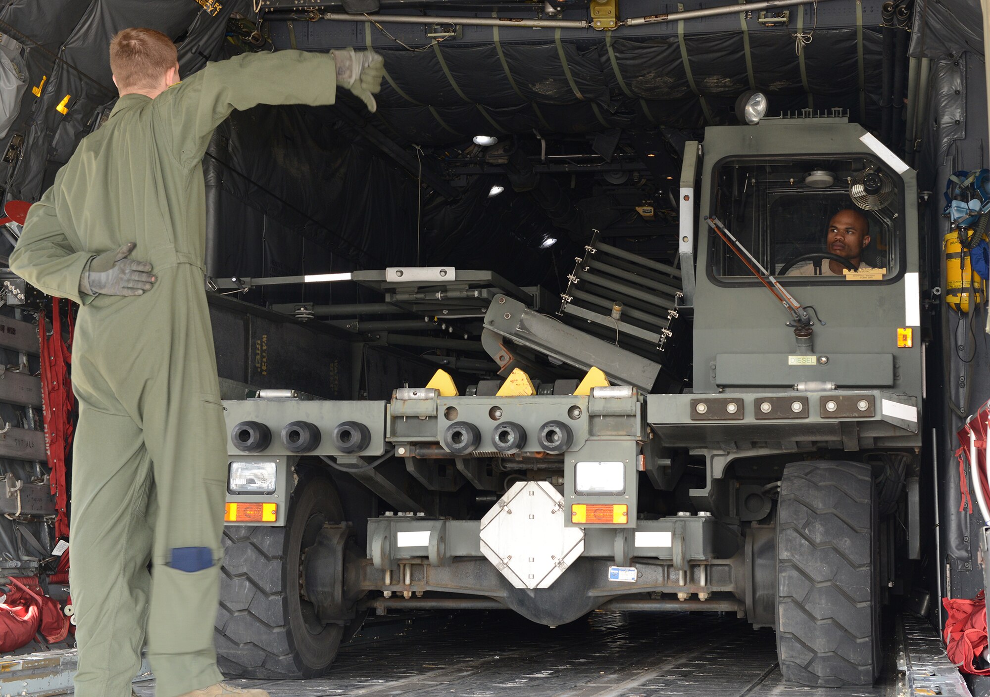 An Airman with the 374th Logistics Readiness Squadron drives a K-loader onto a C-130 Hercules while being ushered by Senior Airman Chris Hofer, 36th Airlift Squadron loadmaster, May 14, 2015, at Yokota Air Base, Japan. As the Pacific Airlift Hub, Yokota would receive and deploy forces and equipment during contingency operations in the Asia-Pacific Region. (U.S. Air Force photo by Senior Airman Desiree Economides/Released)