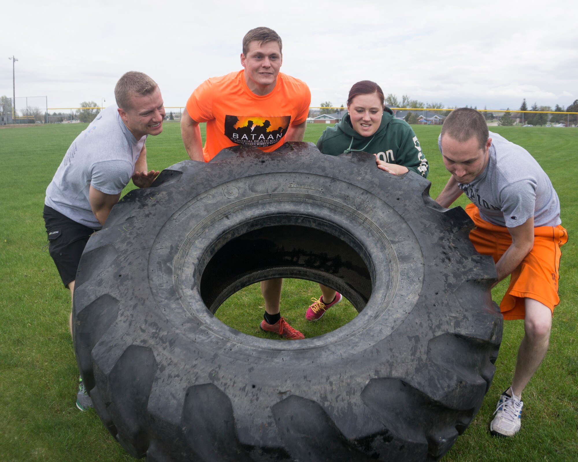 Senior Airman Paul Wilkey, 90th Contracting Squadron, Staff Sgt. Ben Hebert, 90th Communications Squadron, Airman 1st Class Jordan Bailey, 90th Force Support Squadron, and Senior Airman Timothy Mefford, 90th Missile Wing Judge Advocate, lift a 500-pound tire during the team torture event May 13, 2015, on F.E. Warren Air Force Base, Wyo. The event included a 50-yard tire flip, 50-yard log carry, 50-yard body drag, and a 50-yard relay. (U.S. Air Force Photo by Lan Kim)
