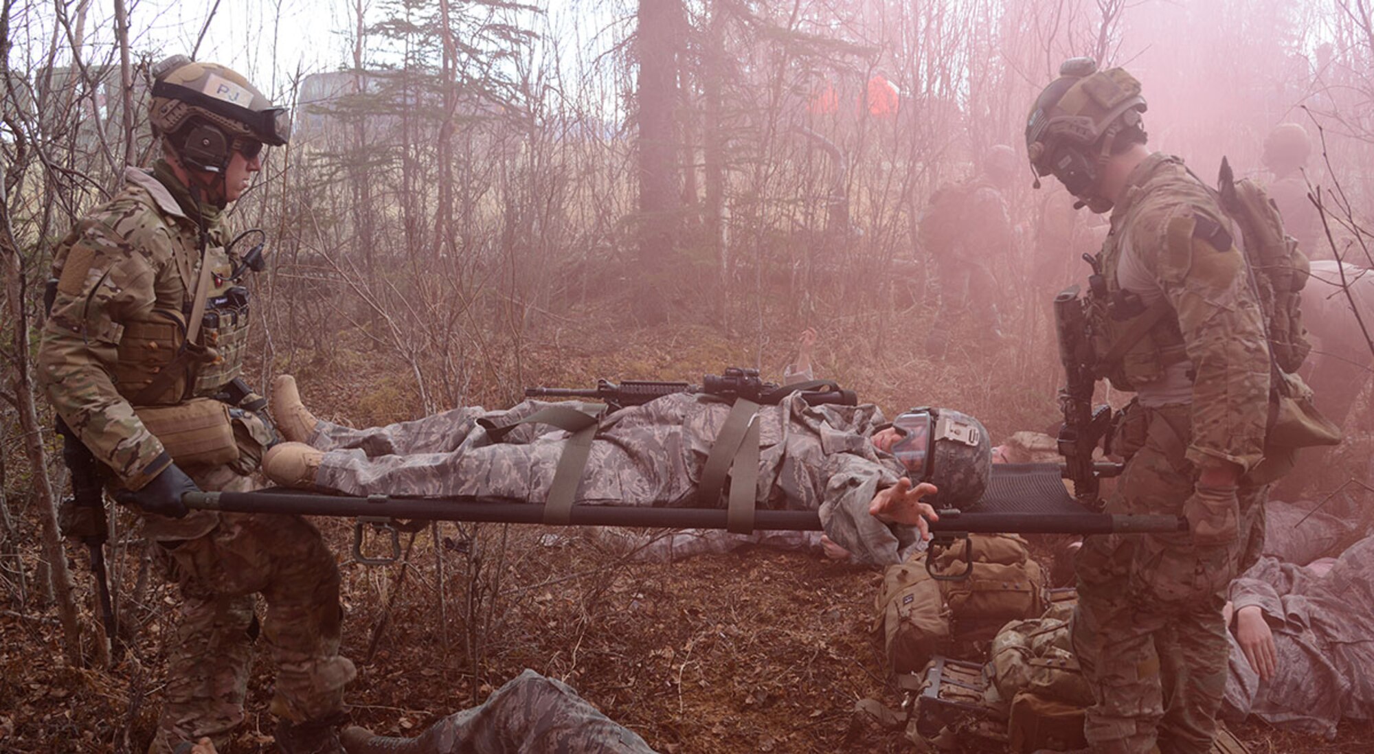 Two Air Force pararescuemen carry a wounded patient to a casualty collection point during an exercise at Joint Base Elmendorf-Richardson, Alaska, April 30. Army soldiers and PJs worked together in the exercise designed to integrate Army and Air Force combat casualty care capabilities. (U.S. Air Force photo/Staff Sgt. Wes Wright)