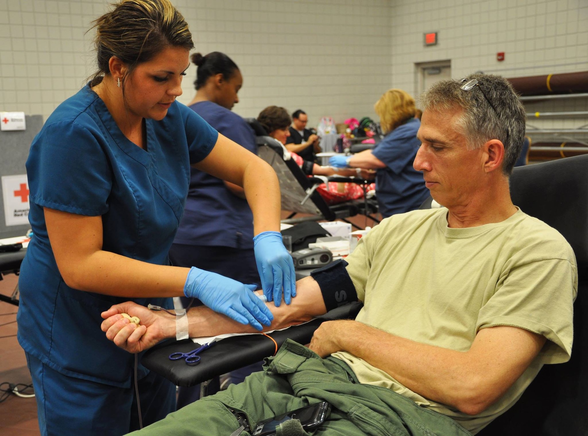 Amanda Fabry, American Red Cross phlebotomist, looks for a vein on Lt. Col. Randy Brink,18th Air Refueling Squadron pilot, during a blood drive May 14, 2015, at McConnell Air Force Base, Kan. Team McConnell is hosting the "Honor Your Hero" blood drive through May 15. For more information, or to register to give blood, check out this story at www.mcconnell.af.mil/news/story.asp?id=123447862, or call 1-800-RED CROSS.  (U.S. Air Force Photo by Tech. Sgt. Abigail Klein)
