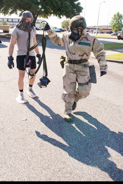 U.S. Air Force Senior Airman Katherine Harrington, 23d Operations Support Squadron, guides Capt. Michael Veltman, 347th Operations Support Squadron flight commander, to a simulated decontamination shower during an Aircrew Contamination Control Area decontamination line training May 8, 2015, at Moody Air Force Base, Ga. The shower is used to ensure all contaminants are eliminated to remove gear. (U.S. Air Force photo by Airman Greg Nash/Released) 