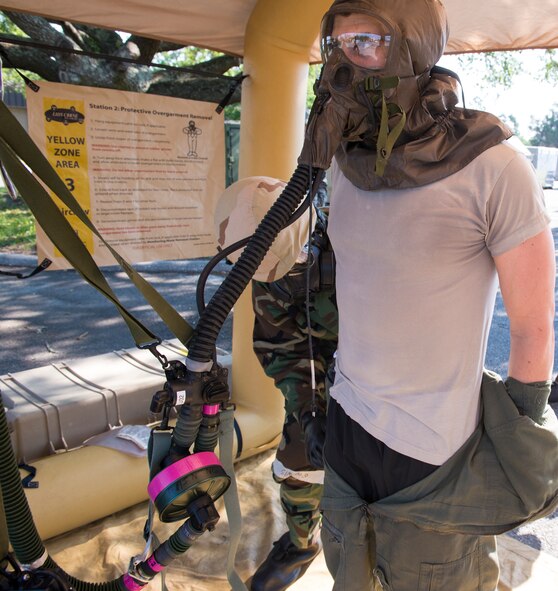 U.S. Air Force Senior Airman Aaron Blaylock, 347th Operations Support Squadron aircrew flight equipment technician, removes Capt. Michael Veltman’s, 347th OSS flight commander, flight suit during an Aircrew Contamination Control Area decontamination line training May 8, 2015, at Moody Air Force Base, Ga. Pilots have all of their clothing removed after a simulated spraying and cleaning to prepare for a decontamination shower. (U.S. Air Force photo by Airman Greg Nash/Released) 