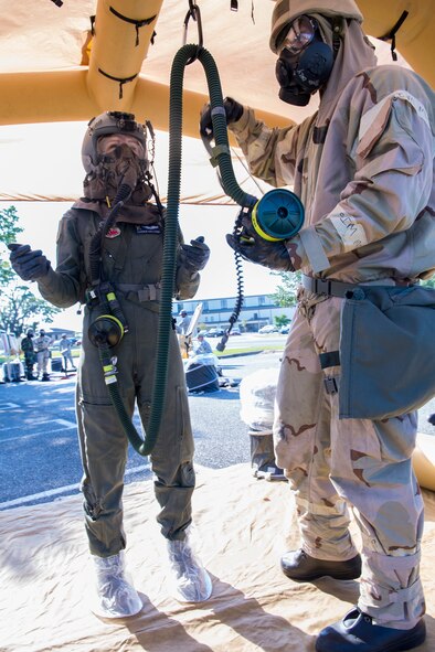 U.S. Air Force Capt. Farren Sullivan, 347th Operations Support Squadron assistant aircrew flight officer, left, waits as Senior Airman Michael Romero, 347th OSS aircrew flight equipment technician, simulates cleaning her aircrew eye and respiratory protection equipment assembly during an Aircrew Contamination Control Area decontamination line training May 8, 2015, at Moody Air Force Base, Ga. The AERP is the aircrew’s equivalent to mission-oriented protective posture (MOPP) 4 gear to protect from chemical, biological, radiological, and nuclear environments. (U.S. Air Force photo by Airman Greg Nash/Released)  