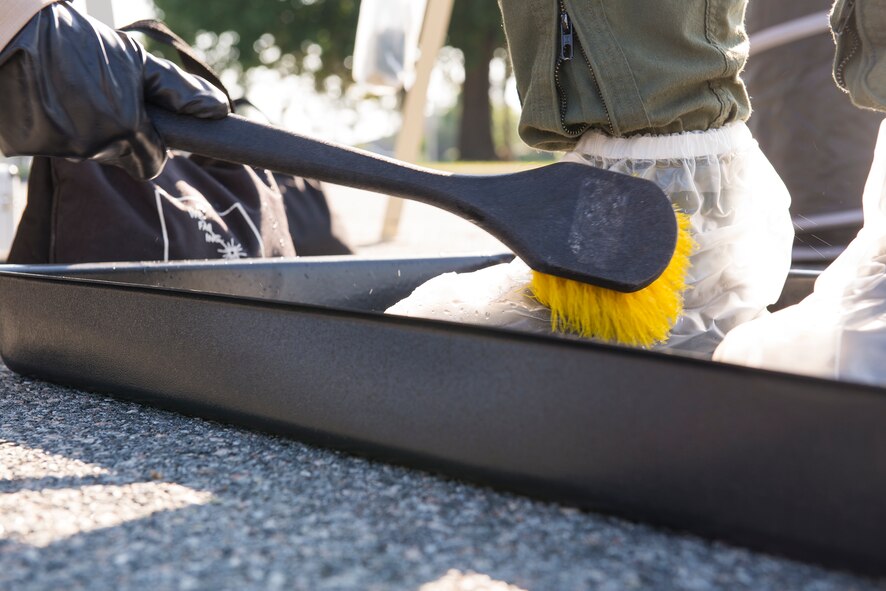 U.S. Air Force Senior Airman Jessica Burrell, 347th Operations Support Squadron aircrew flight equipment technician, cleans the boots of Capt. Farren Sullivan, 347th OSS assistant aircrew flight officer, during an Aircrew Contamination Control Area decontamination line training May 8, 2015, at Moody Air Force Base, Ga.  The training is implemented to teach pilots the process of the decontamination line after a chemical or biological attack. (U.S. Air Force photo by Airman Greg Nash/Released)