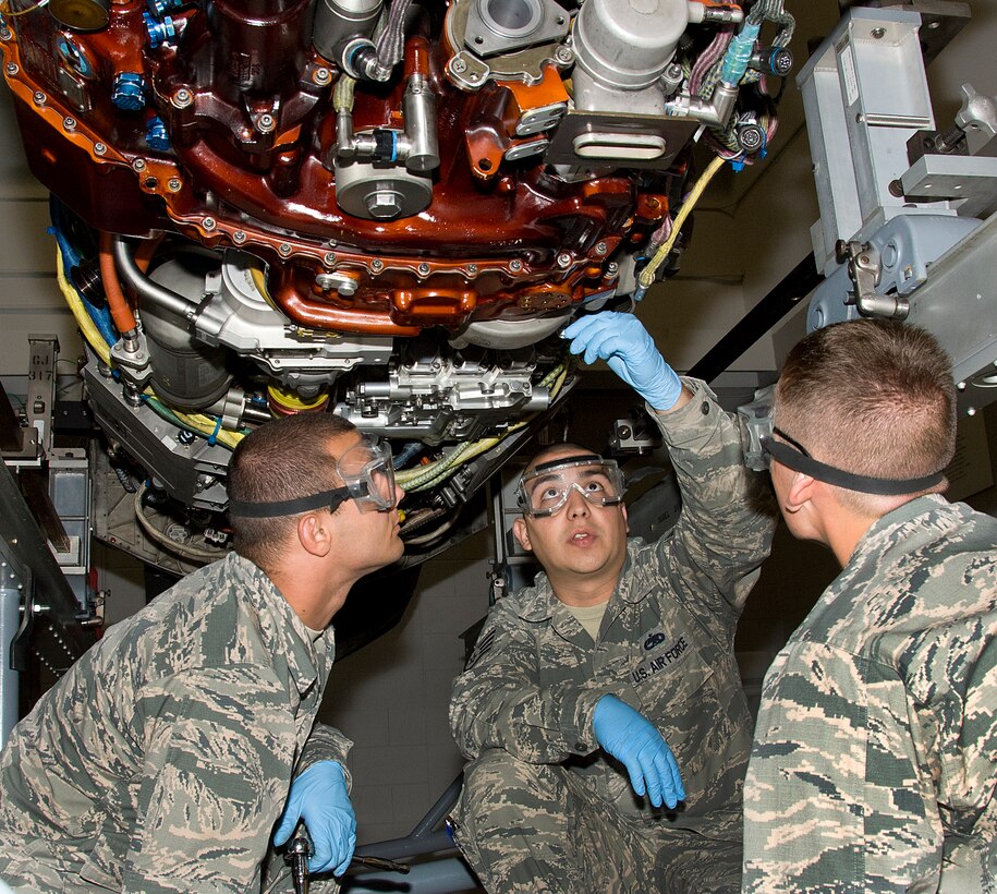 U.S. Air Force Staff Sgt. Edgar Cadenas, 362nd Training Squadron crew chief instructor, demonstrates how to replace an engine fuel filter on a F119-PW-100 engine for the F-22 steps to Airmen Dylan Tyrrell and Airmen Matei Craven, students from 362nd Training Squadron at Sheppard Air Force Base, Texas May 13, 2015. Students learn how to perform inspections to ensure there are no deficiencies that may hinder an Aircraft's flying capabilities. (U.S.) Air Force photo by Danny Webb/Released)