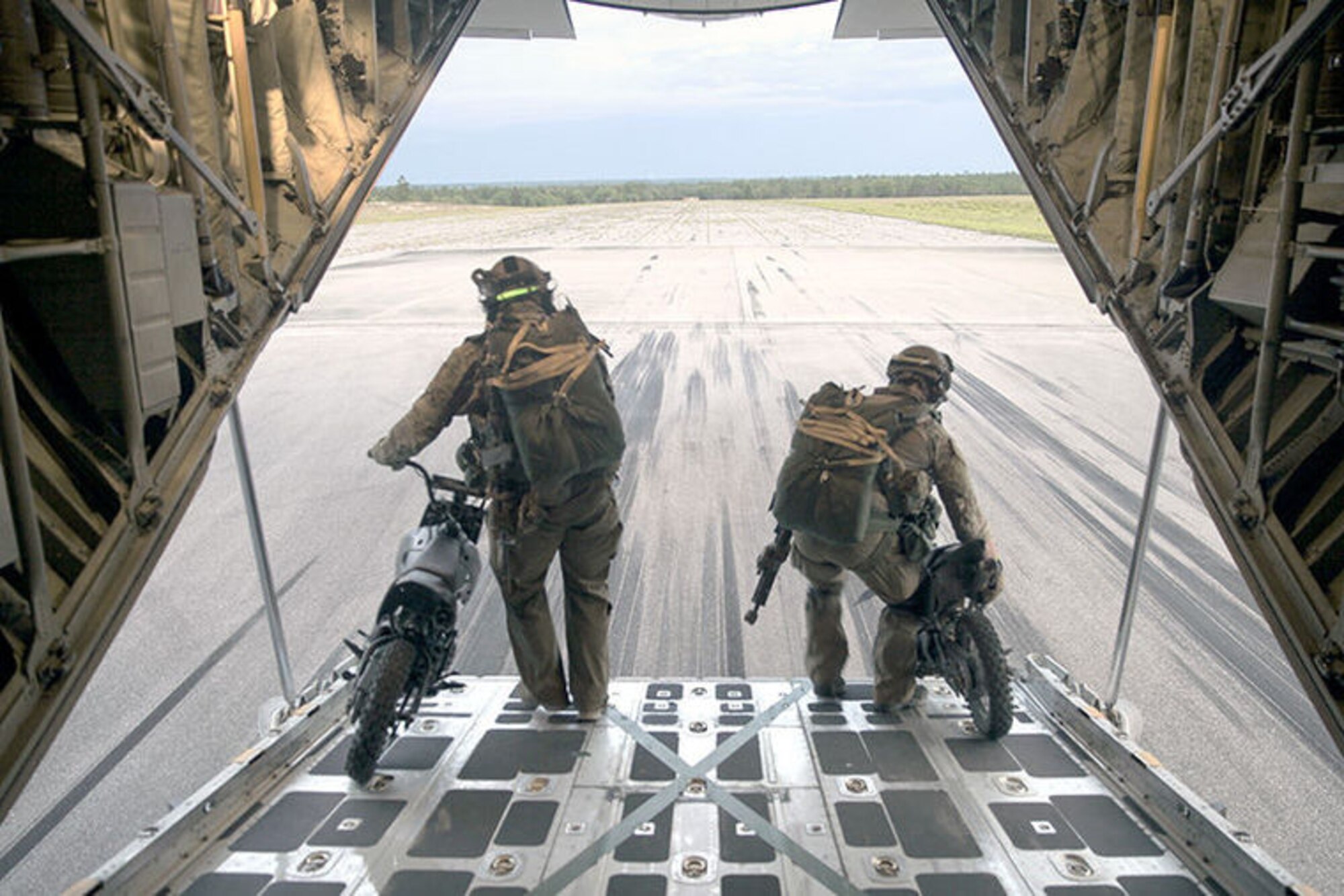 Two 123rd STS personnel off load 50 cc mini bikes to stage on a runway at an Eglin Air Force Base drop zone, prior to a static line jump and jump clearing team mission from a KC-130J Super Hercules belonging to Marine Aerial Refueler Transport Squadron 252, during Emerald Warrior 2015, April 28, 2015. The mini bikes are used to patrol down the air strip before the plane lands to ensure there is no debris or hostile forces near the landing zone. Emerald Warrior is a joint exercise led by Air Force Special Operations Command that provides pre-deployment training for U.S. and partner nation special operations forces and interagency elements.