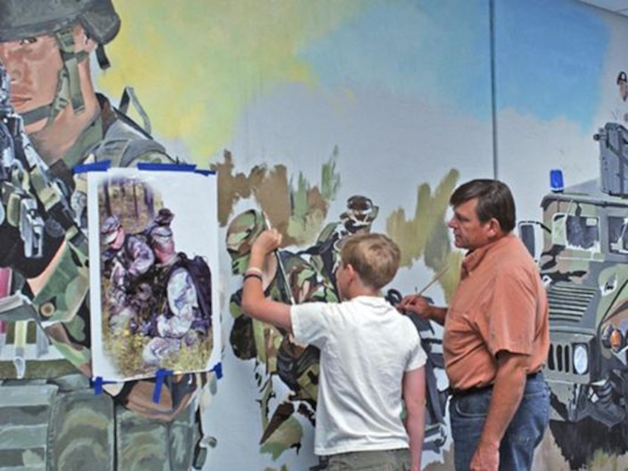 Retired Senior Master Sgt. Bob Stillwell and his son, Bobby, draw a mural at the 341st Missile Wing headquarters at Malmstrom Air Force Base, Mont.  Together they created the mural in honor of security forces Airmen. (courtesy photo)