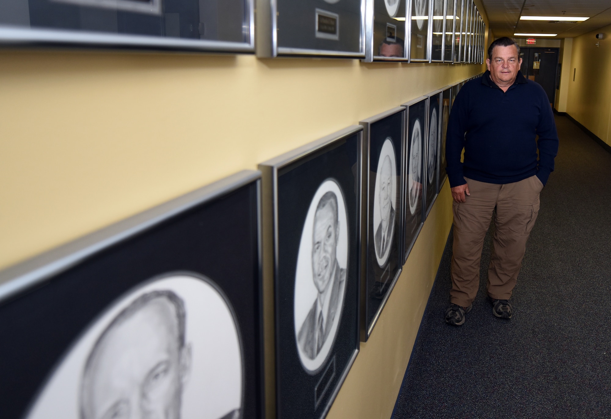 Retired Senior Master Sgt. Bob Stillwell stands in front of his drawings of former base commanders at the 341st Missile Wing Headquarters May 13, 2015 at Malmstrom Air Force Base, Mont.  Stillwell will retire in May of this year after more than 20 years of active-duty service and 14 years as a civilian illustrator for the wing. (U.S. Air Force photo/Chris Willis)