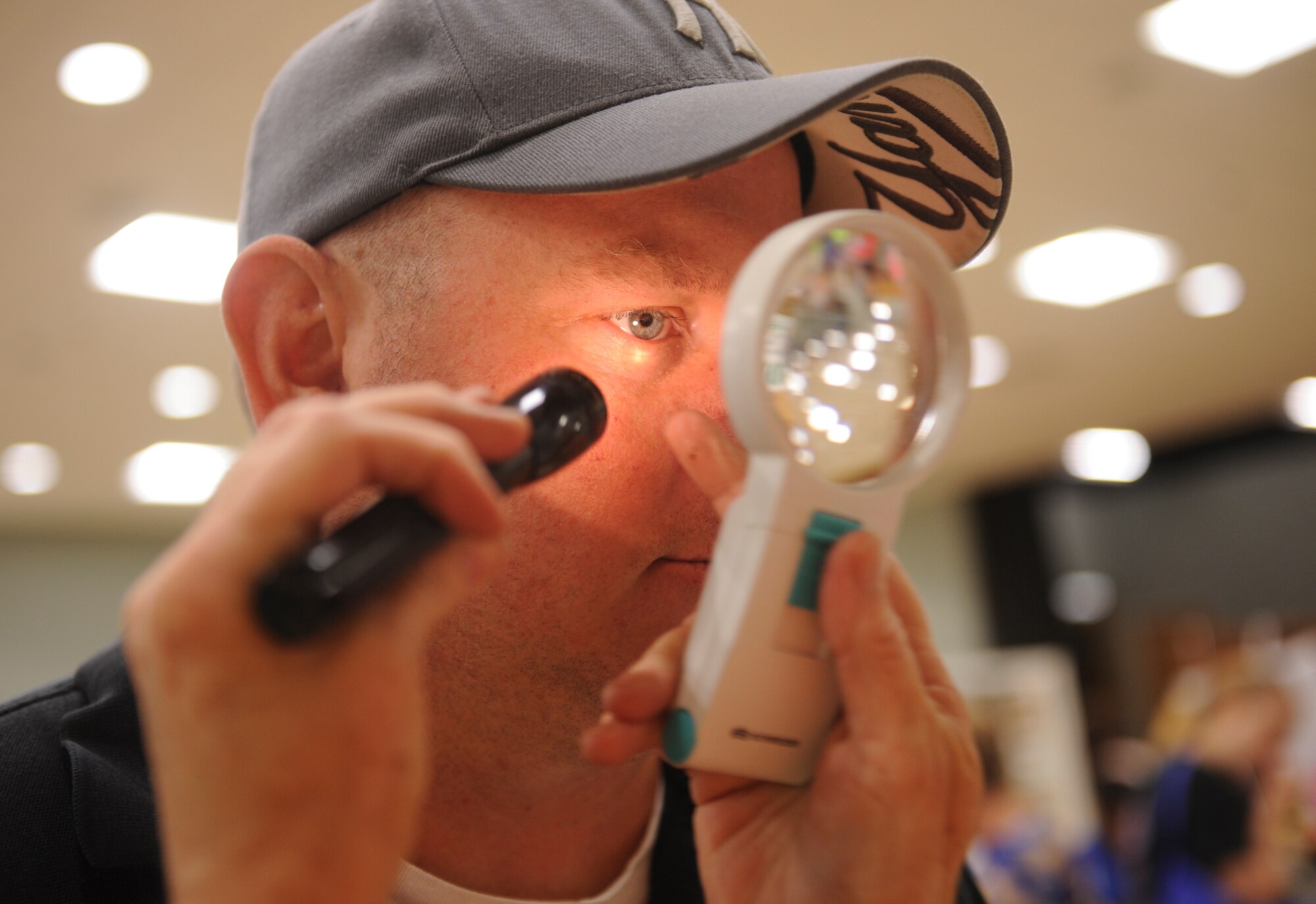 Cathy Uhl, a certified natural health professional, examines Doug Carlton’s eye at the 2nd Annual Military  Spouse Appreciation Bazaar May 8, 2015, at Little Rock Air Force Base, Ark. The Airman and Family Readiness Center has information on events and activities for military spouses. Call (501) 987-6801 for more information. (U.S. Air Force photo by Senior Airman Scott Poe)