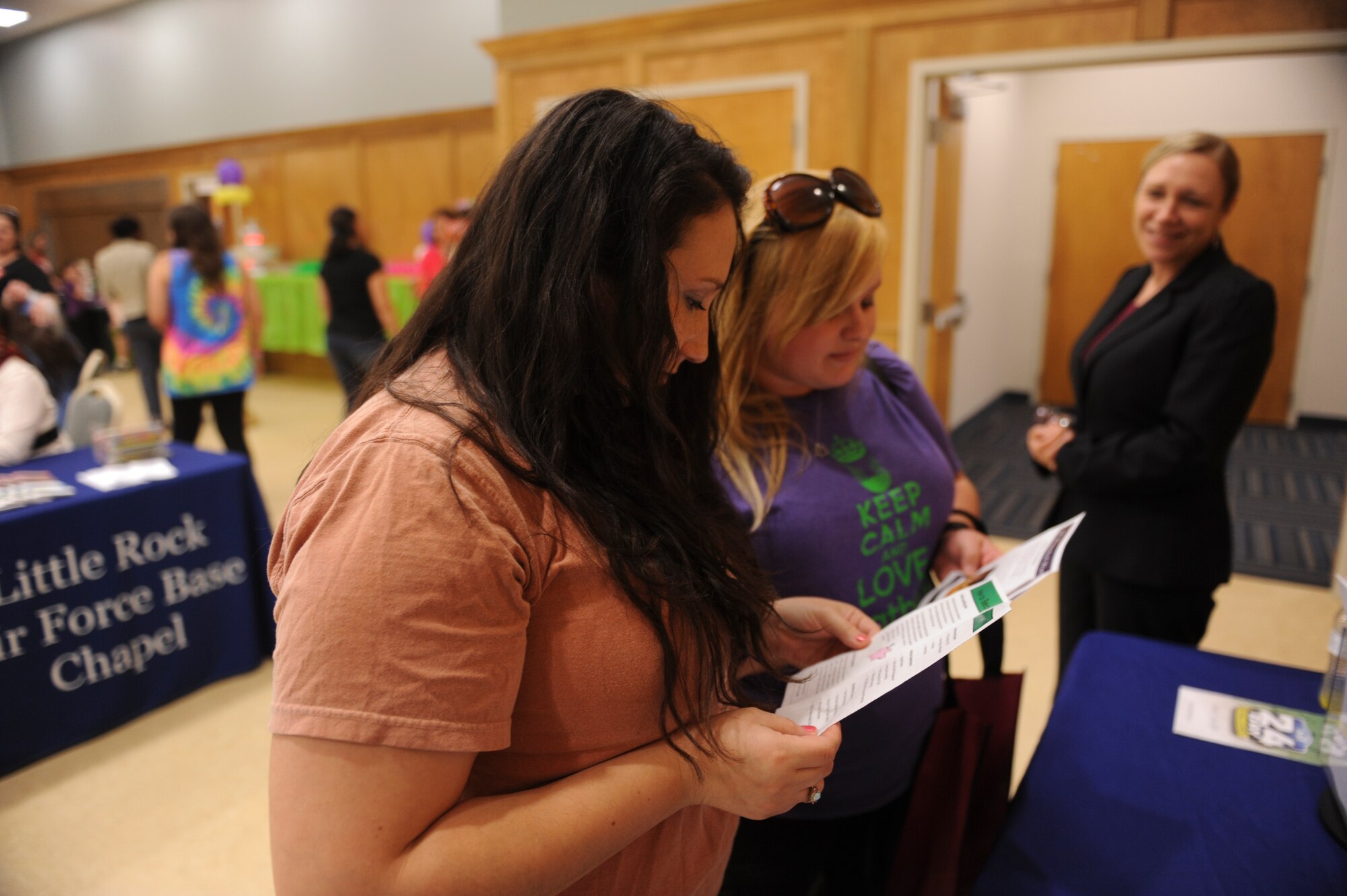 Sam Schmitz and Alexis Graves read about different classes and opportunities offered by the Airman and Family Readiness Center at the 2nd Annual Military  Spouse Appreciation Bazaar May 8, 2015, at Little Rock Air Force Base, Ark. The event provided opportunities for spouses to learn about sources available to them as well as foster friendships with other spouses. (U.S. Air Force photo by Senior Airman Scott Poe)