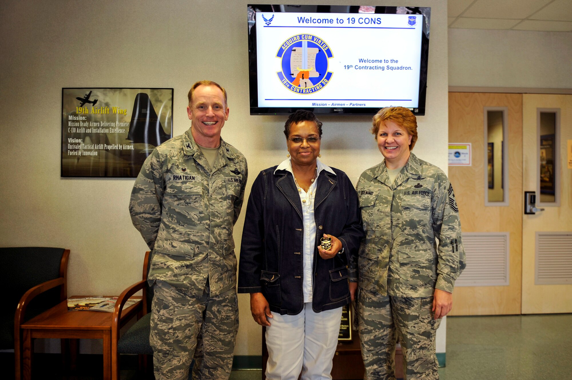 Col. Patrick Rhatigan, 19th Airlift Wing commander, along with Chief Master Sgt. Rhonda Buening, 19th Airlift Wing command chief, congratulate Maritza Wine, a 19th Contracting Squadron contract specialist, for her selection as Combat Airlifter of the Week May 11, 2015, at Little Rock Air Force Base, Ark. Wine expertly managed 14 contracts valued at $8 million providing critical services to three Wing's. (U.S. Air Force photo by Senior Airman Stephanie Serrano)
