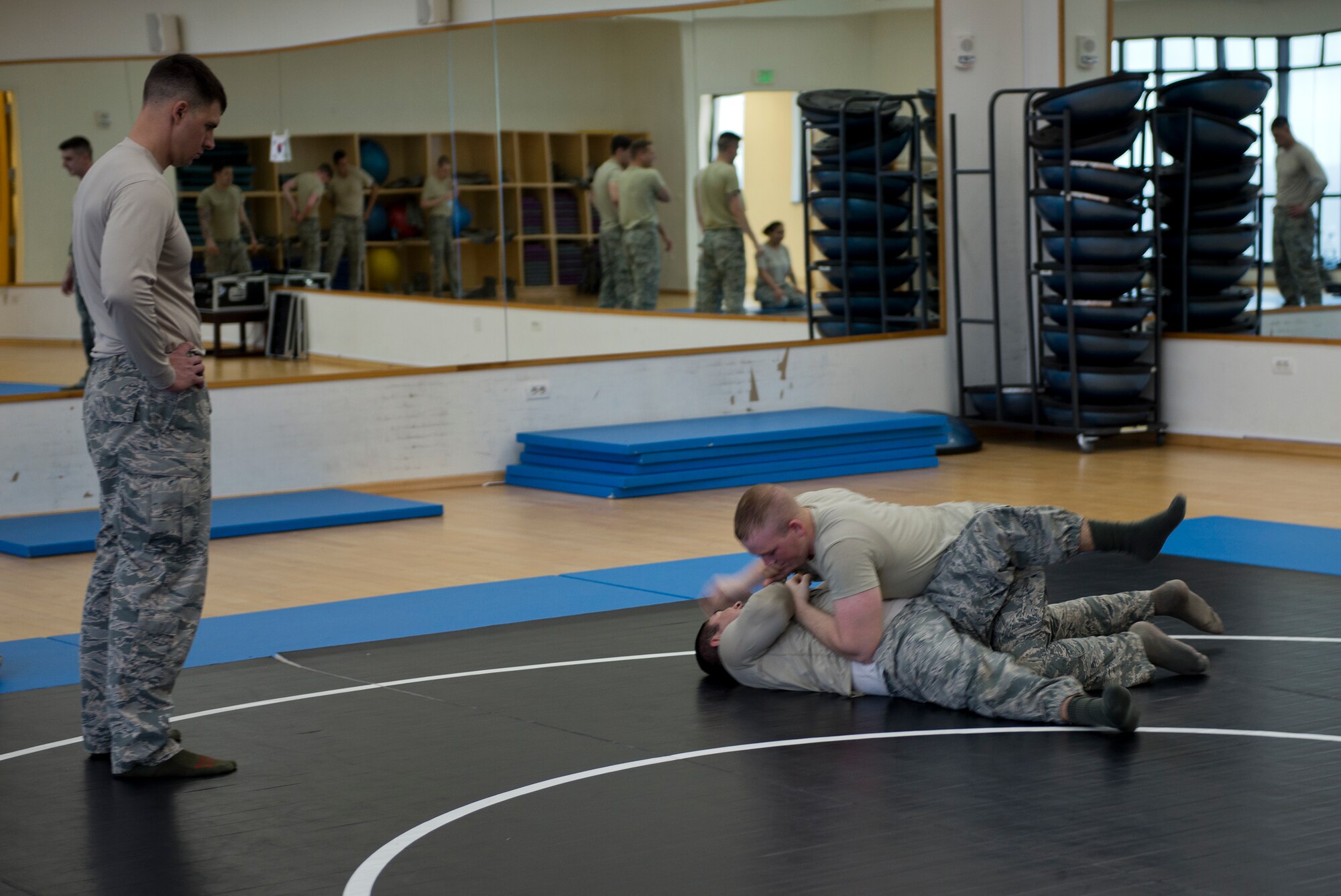 Tech. Sgt. Chance Farmer, 65th Security Forces Squadron noncommissioned officer in charge of training, observes Airman 1st Class Kevin Jones, 65th SFS patrolman, demonstrate the combatives moves he learned against Staff Sgt. Giobany Gracidas, 65th SFS flight chief, during a class at the Chace Fitness Center on Lajes Field, Azores, Portugal, March 31, 2015. Farmer provides the Defenders with this and other important training to keep them ready to accomplish thier mission. (U.S. Air Force photo/Staff Sgt. Zachary Wolf)