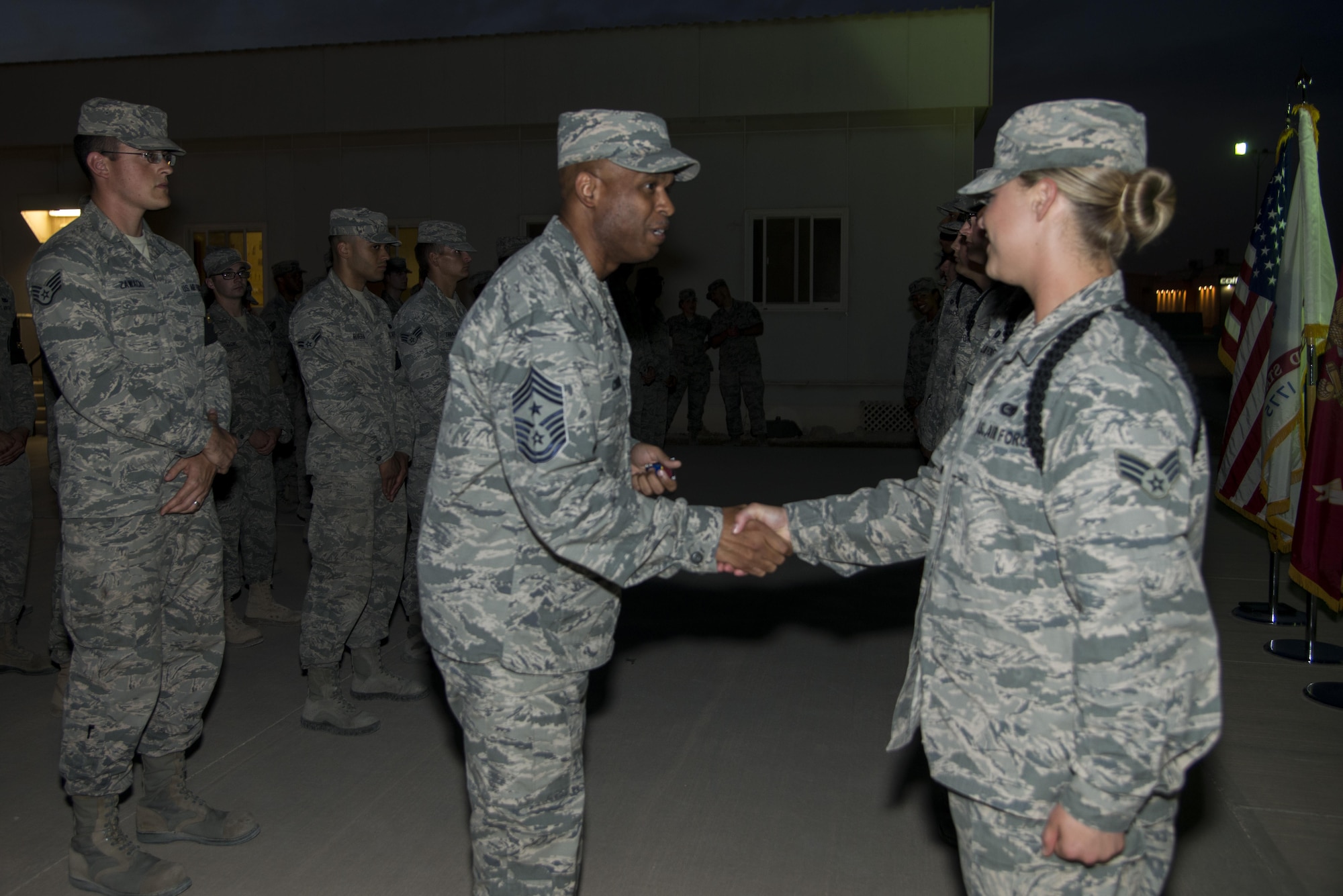 Chief Master Sgt. Danny Crudup, 379th Air Expeditionary Wing command chief, presents his coin to Senior Airman Alyssa Breeding, an honor guard instructor, from the 379th Expeditionary Logistics Readiness Squadron, May 11, 2015, at the Memorial Plaza on Al Udeid Air Base, Qatar.  Crudup passed his coins out to all the honor guard instructors for their contribution in assisting the base honor guard in presenting an outstanding image at their wing-wide events. (U.S. Air Force photo/Tech. Sgt. Douglas)
