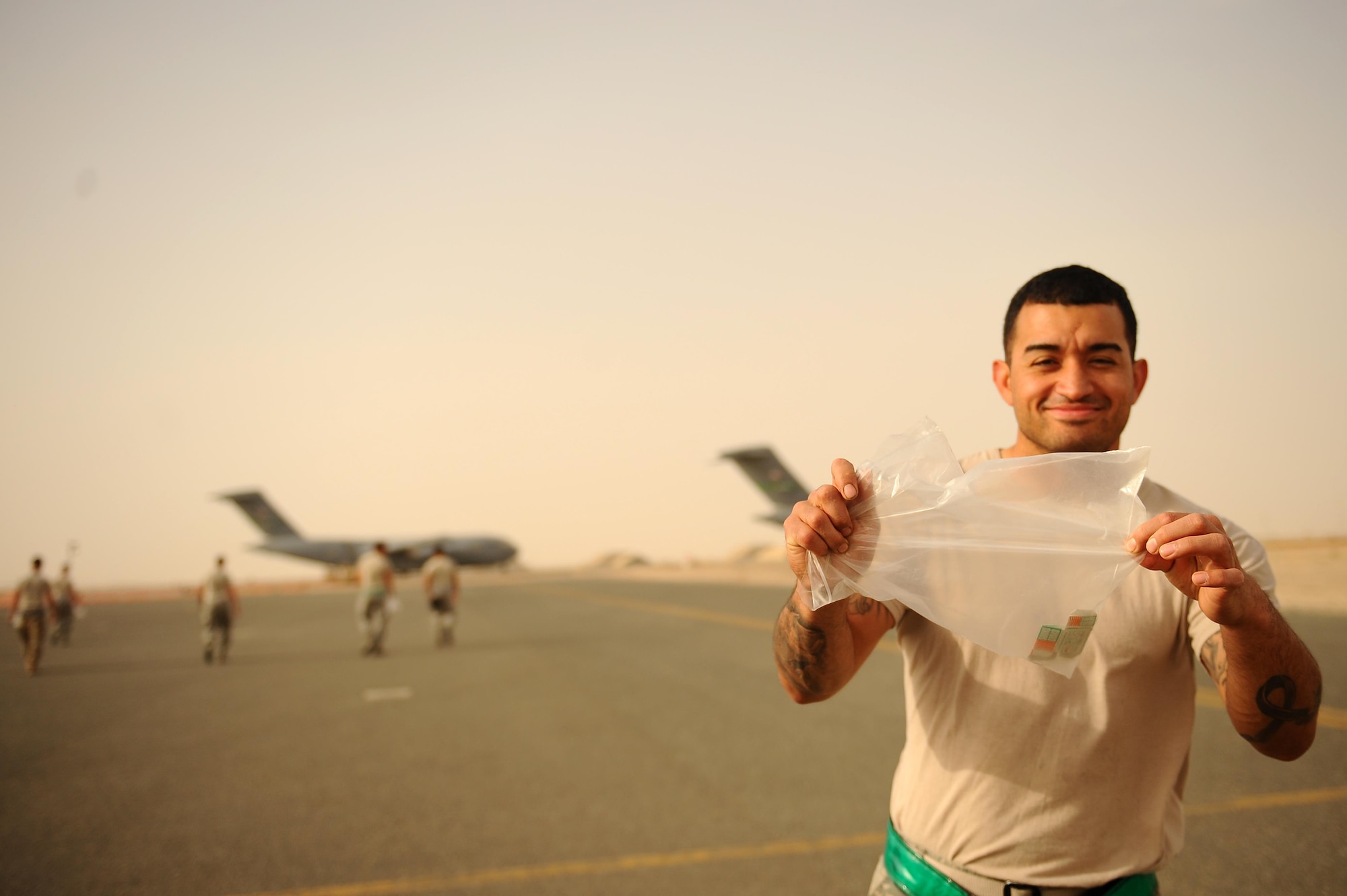 A U.S. Airman displays his bag of “FOD” or Foreign Object Debris during a clean-up of the flightline at an undisclosed location in Southwest Asia, May 15, 2015. Airmen routinely clear any trash or objects from the flightline which could cause engine or structural damage to aircraft.  (U.S. Air Force photo/Tech. Sgt. Brittany E. Jones)