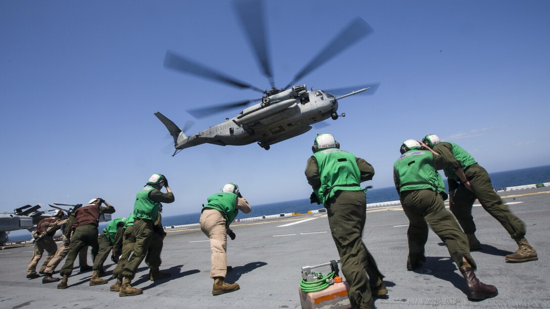 U.S. Marines with the 26th Marine Expeditionary Unit (MEU), brace the rotor wash of a CH-53 Super Stallion while conducting flight operations aboard the USS Kearsarge (LHD 3), in the Atlantic Ocean, May 9, 2015, during PHIBRON-MEU Integrated Training. PMINT is a joint training event the 26th MEU, supporting elements and PHIBRON 4 are conducting in preparation for their deployment to the 5th and 6th Fleet areas of responsibility later this year. (U.S. Marine Corps photo by Lance Cpl. Andre Dakis/26th MEU Combat Camera/Released)