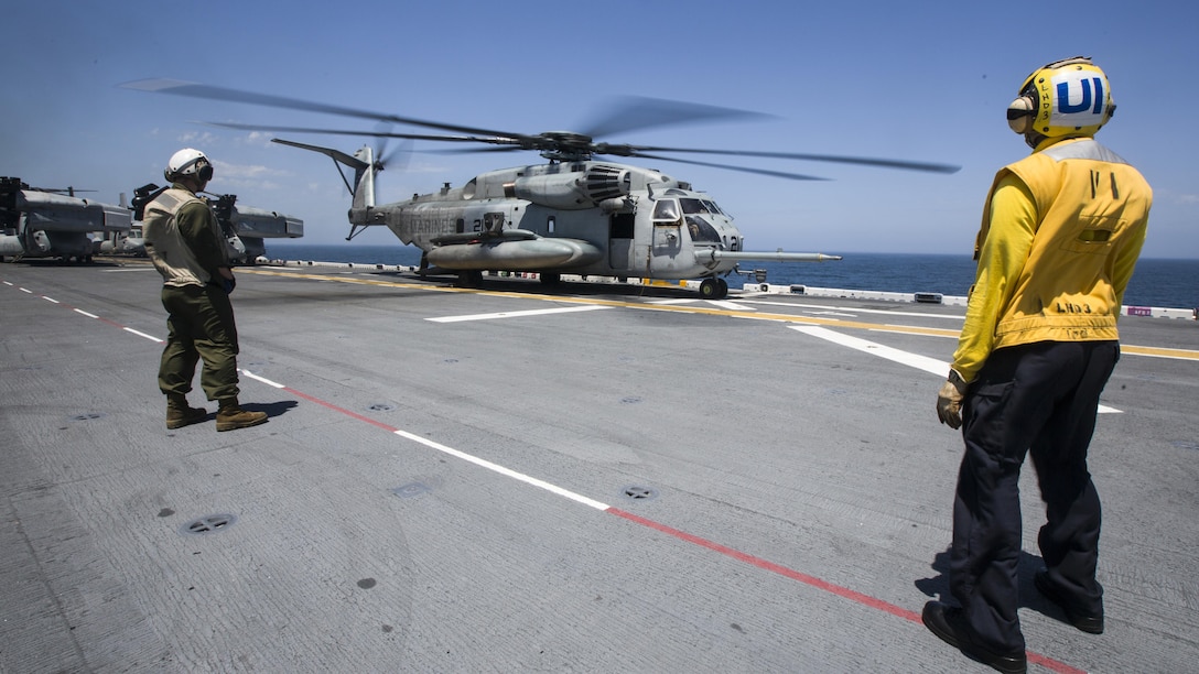 U.S. Marines and sailors with the 26th Marine Expeditionary Unit, and Amphibious Squadron 4 (PHIBRON) wait for a CH-53 Super Stallion to take off while conducting flight operations aboard the USS Kearsarge (LHD 3), in the Atlantic Ocean, May 9, 2015, during PHIBRON-MEU Integrated Training (PMINT). PMINT is a joint training event the 26th MEU, supporting elements and PHIBRON 4 are conducting in preparation for their deployment to the 5th and 6th Fleet areas of responsibility later this year. (U.S. Marine Corps photo by Lance Cpl. Andre Dakis/26th MEU Combat Camera/Released)