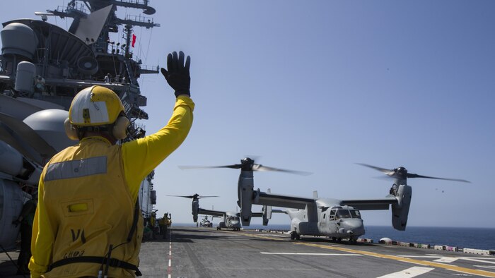 A U.S. Navy sailor with Amphibious Squadron 4 (PHIBRON) signals an MV-22B Osprey assigned to the 26th Marine Expeditionary Unit, while conducting flight operations aboard the USS Kearsarge (LHD 3), in the Atlantic Ocean, May 9, 2015, during PHIBRON-MEU Integrated Training. PMINT is a joint training event the 26th MEU, supporting elements and PHIBRON 4 are conducting in preparation for their deployment to the 5th and 6th Fleet areas of responsibility later this year. (U.S. Marine Corps photo by Lance Cpl. Andre Dakis/26th MEU Combat Camera/Released)