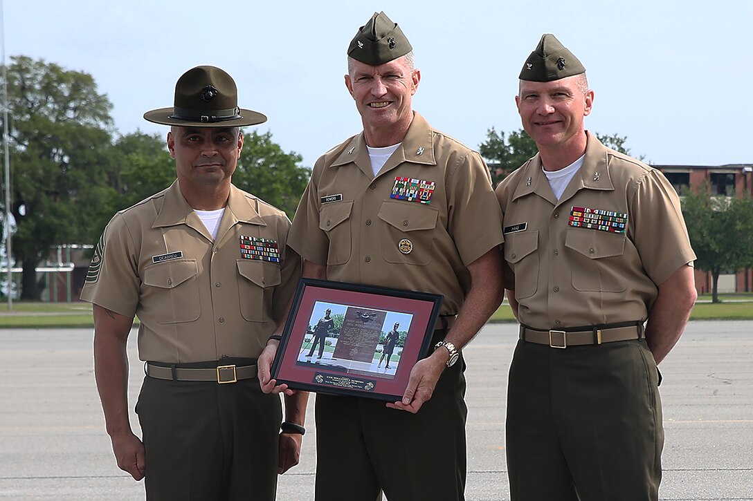 Col. William Bowers, Commanding Officer of 6th Marine Corps District, stands in between Sgt. Maj. Nicholas Deabreu and Col. Daniel Haas during graduation aboard Parris Island, S.C., May 15, 2015. Bowers holds a picture that was presented by the Marines present, commemorating his time as the parade reviewing officer. (Official Marine Corps photo by Cpl. John-Paul Imbody)