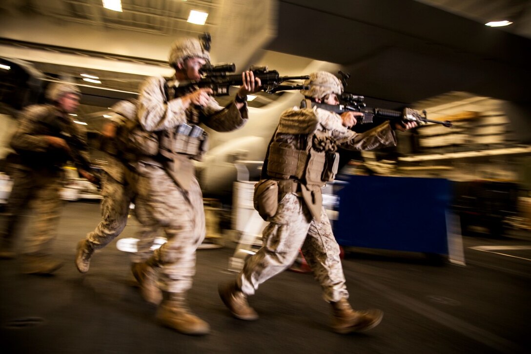 U.S. Marines with Lima Company, Battalion Landing Team 3rd Battalion, 1st Marine Regiment, 15th Marine Expeditionary Unit, rush toward their objective in the hangar bay of the USS Essex (LDH 2) at sea in the Pacific Ocean, May 14, 2015. Lima Co. is refreshing skills like house clearing to maintain their readiness during their seven-month deployment with the 15th MEU (U.S. Marine Corps photo by Cpl. Elize McKelvey/Released)