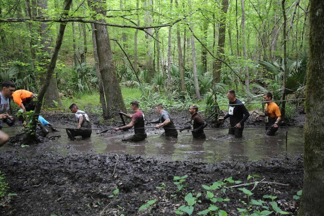 Participants of the MARSOC Mud, Sweat and Tears run wade through a trench filled with mud, April 25, 2015, at Stone Bay, on Marine Corps Base Camp Lejeune, N.C. (U.S. Marine Corps photo by Cpl. Steven Fox/Released)