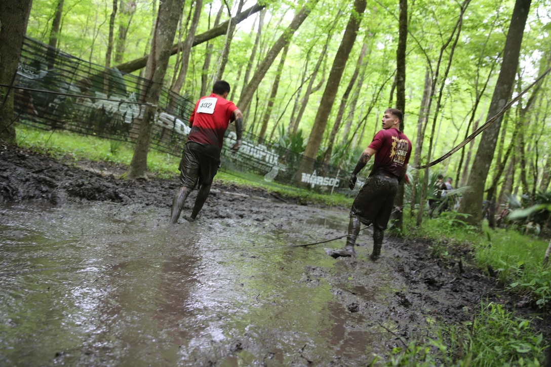 Two MARSOC Mud, Sweat and Tears run participants exit one of the larger mud-filled trenches featured in the mud run course aboard Stone Bay, on Marine Corps Base Camp Lejeune, N.C., April 25, 2015. (U.S. Marine Corps photo by Cpl. Steven Fox/Released)