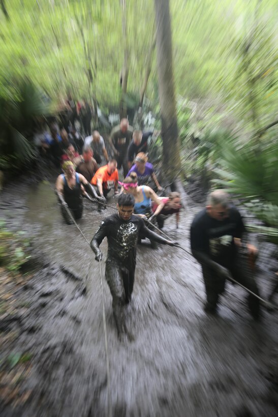 Participants of the MARSOC Mud, Sweat and Tears run make their way through one of the larger mud-filled trenches featured in the mud run course aboard Stone Bay, on Marine Corps Base Camp Lejeune, N.C., April 25, 2015. (U.S. Marine Corps photo by Cpl. Steven Fox/Released)
