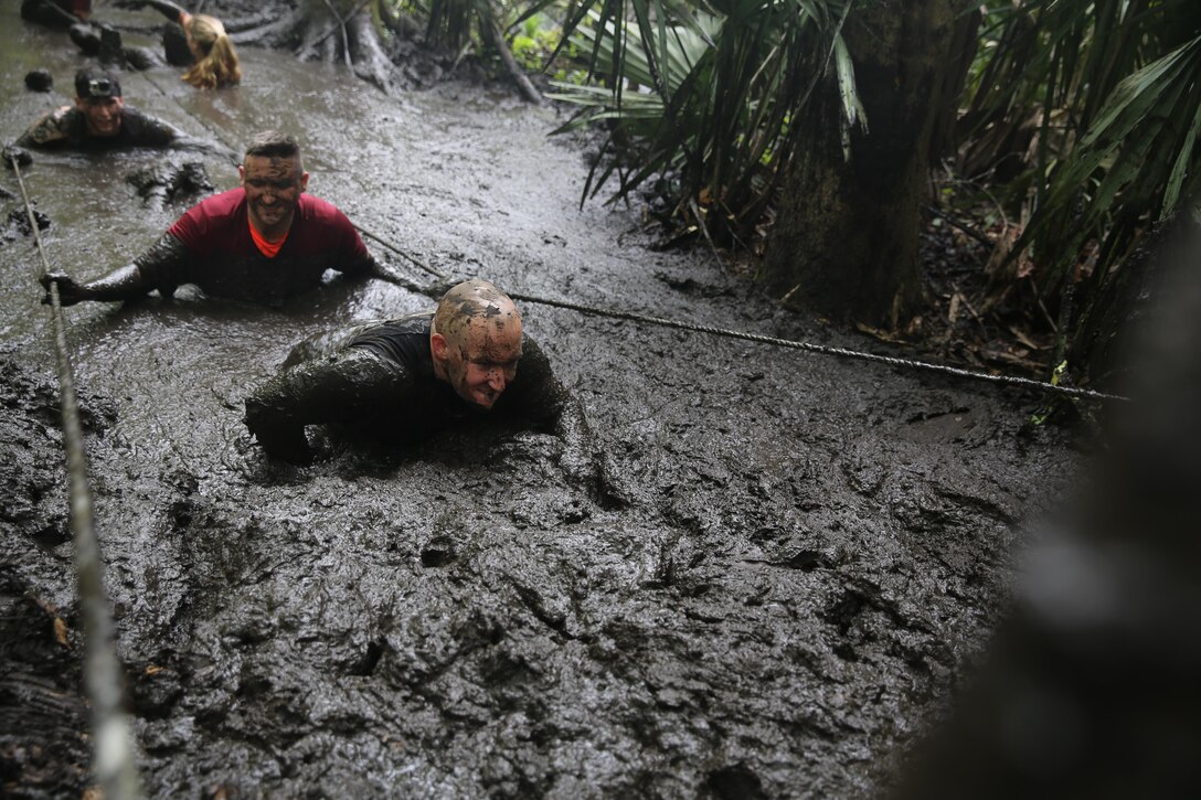 Participants of the MARSOC Mud, Sweat and Tears run wade through one of the larger mud-filled trenches featured in the mud run course aboard Stone Bay, on Marine Corps Base Camp Lejeune, N.C., April 25, 2015. (U.S. Marine Corps photo by Cpl. Steven Fox/Released)