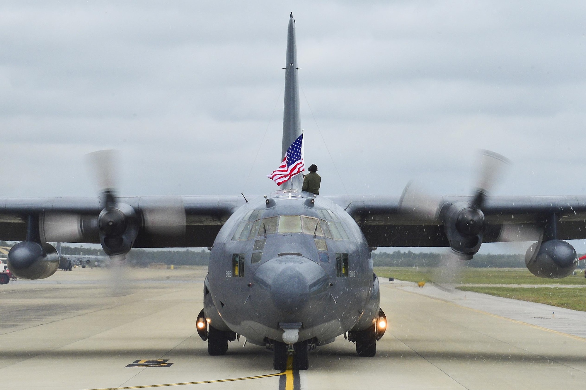 Tech. Sgt. Bruce Ramos, 1st Special Operations Group Detachment 1 radio operator, raises an American Flag from an MC-130P Combat Shadow while it taxis at Hurlburt Field, Fla., May15, 2015. The final two MC-130P Combat Shadow aircraft in the Air Force landed for the last time at Hurlburt Field, Fla., in front of more than 400 people and will take their last flight to the boneyard at Davis-Monthan Air Force Base, Arizona, June 1. (U.S. Air Force photo/Senior Airman Jeff Parkinson)