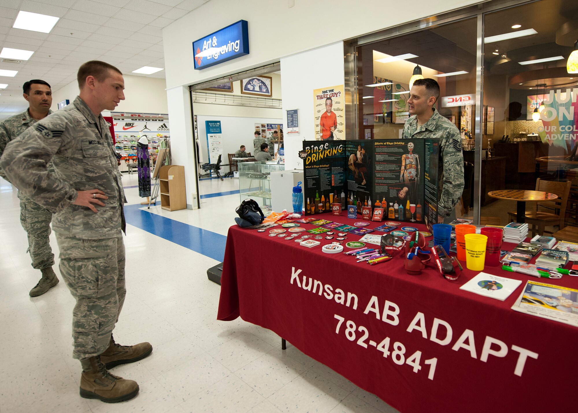 Senior Airman Charles McClung, 8th Civil Engineer Squadron administrative journeyman (left), visits the crime prevention booth, manned by Tech. Sgt. Paul Lamelin, 8th Security Forces Squadron resource protection NCO in charge (right), at the Base Exchange during National Police Week May 13, 2015, at Kunsan Air Base, Republic of Korea. This year’s observance of police week recognized the Wolf Pack’s varied skillsets by highlighting security forces role in protecting the people, property and resources of the U.S. Air Force, as well as the role every Airman plays in crime prevention. (U.S. Air Force photo by Senior Airman Katrina Heikkinen/Released)