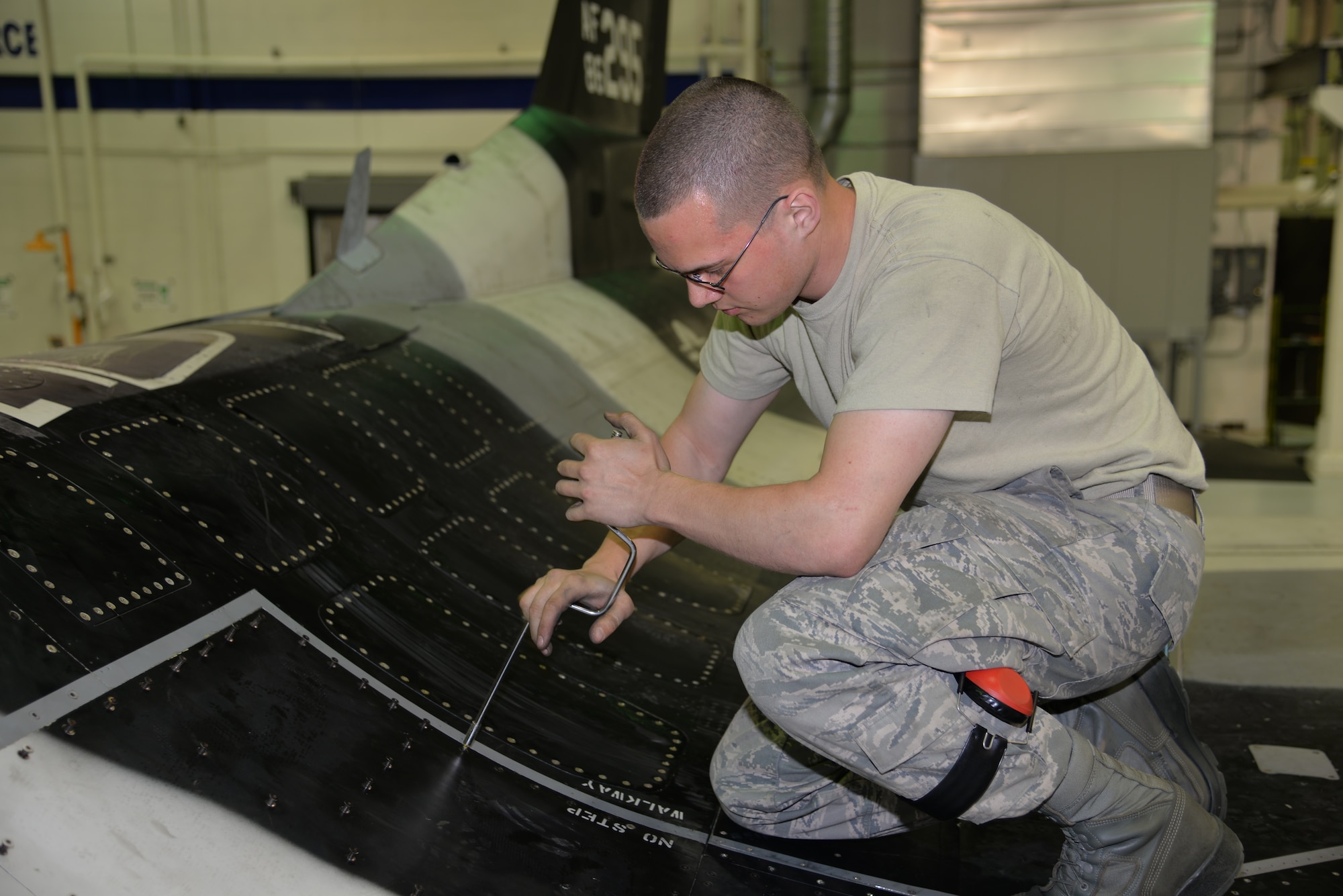 Airman 1st Class Peter Christian, a 354th Aircraft Maintenance Squadron weapons load crew member, secures panels to the body of an F-16 Fighting Falcon aircraft assigned to the 18th Aggressor Squadron. When repairs in the phase inspection section are complete, Airmen close the panels and prepare the jet to return to the flying training mission as quickly as possible. (U.S. Air Force photo by Staff Sgt. Kirsten Wicker/Released)    