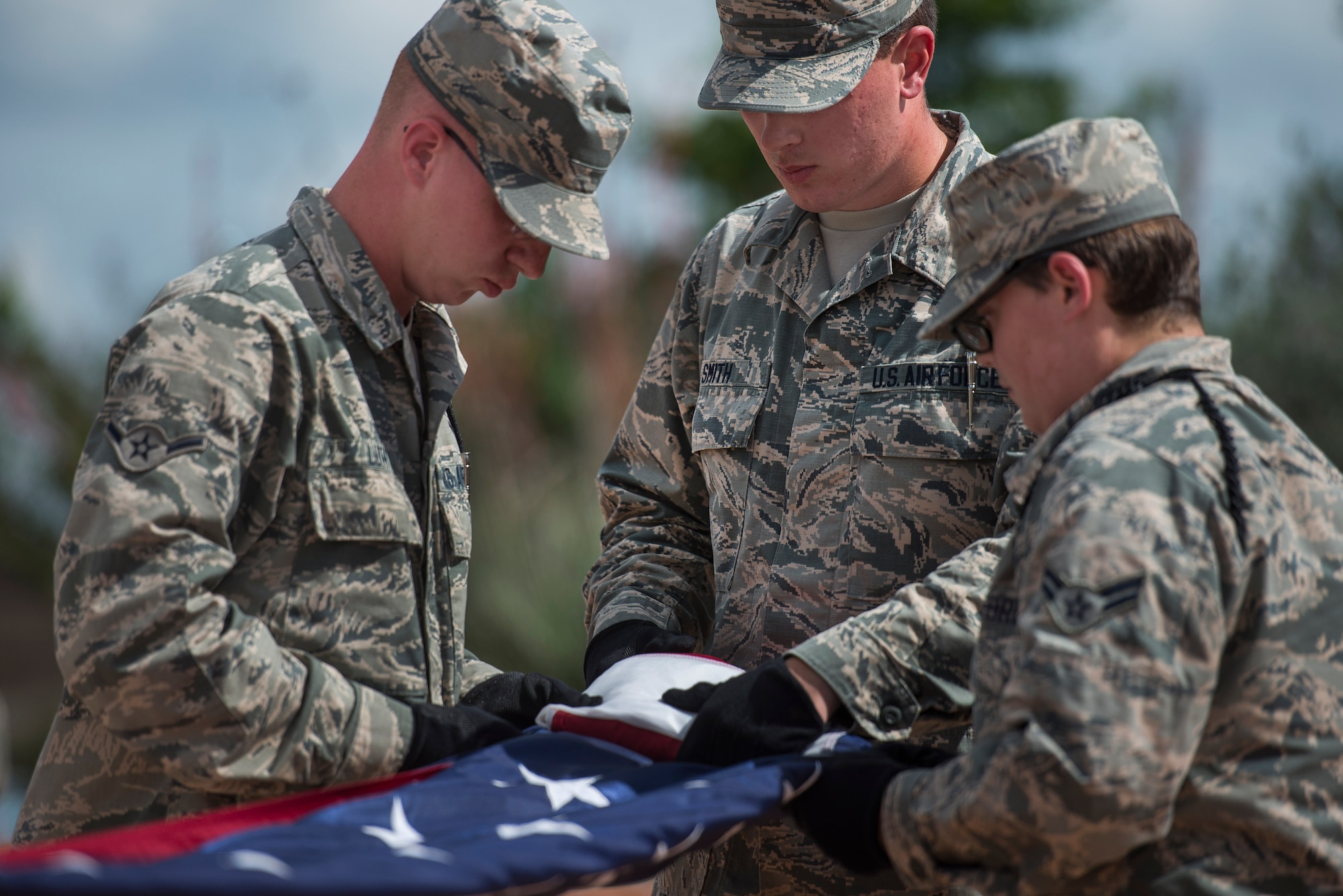 Airman Brian Smith, 365th Training Squadron flag bearer, (middle), folds flag with Airman Sean Luth, 361st Training Squadron, (left), and Airman 1st Class Heather Clapp, 365th TRS, (right), both flag security detail Airmen during the National Police Week retreat ceremony at Sheppard Air Force Base, Texas, May 15, 2015. The 82nd Training Wing Airmen collaborated with the local Wichita Falls Police department to honor all officers who lost their lives in the line of duty. (U.S. Air Force photo by Senior Airman Kyle Gese/Released)