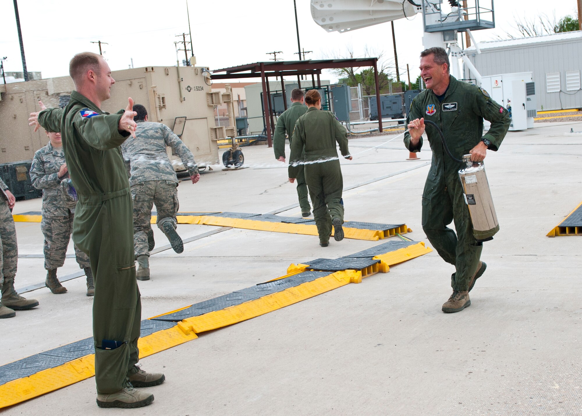 Colonel James Thompson, 49th Wing vice commander steals water and sprays members after stepping out of an Remotely Piloted Aircraft, Ground Control Station upon completing his final flight at Holloman Air Force Base, N.M. May 15, 2015. Members of the 29th and 9th Attack Squadrons showered Thompson with water as part of a tradition dating back to World War II.  (U.S. Air Force photo by Senior Airman Leah Ferrante/released) 