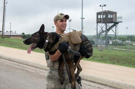 Staff Sgt. Mark Anthony Devine, 802nd Security Forces Squadron military working dog handler, carries his military working dog, Jany, during the Police Week K-9 and Military Working Dog competition May 14, 2015, at Joint Base San Antonio-Lackland Medina Annex. Teams from JBSA, Altus Air Force Base, Oklahoma, Dyess Air Force Base, Texas, Bexar County Sheriff’s Office K-9 unit and the Corpus Christie Police Patrol K-9 Unit displayed various exercises with their K-9 or working dog such as explosives and narcotics detection, controlled aggression, intruder detection, building search, K-9 carry, first aid demonstration and a ruck march.  The event was the first K-9 competition organized by the 802nd Security Forces Squadron and included 17 military and civilian teams. (U.S. Air Force photo by Johnny Saldivar/released)