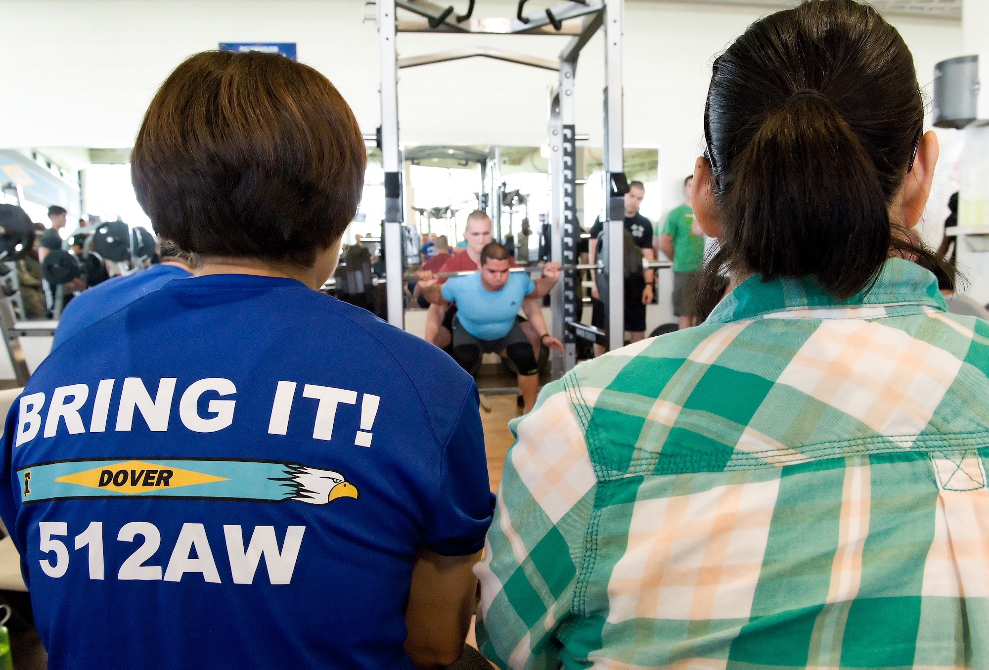 Carolina Rodriquez, left, and Veronica Aceveda, right, watch Andrew Boulier squat during the powerlifting competition May 8, 2015, at the Fitness Center on Dover Air Force Base, Del. Boulier placed first in the male 198-pound weight class with a combined total of 1,065 pounds for the squat, bench press and deadlift. (U.S. Air Force photo/Roland Balik)