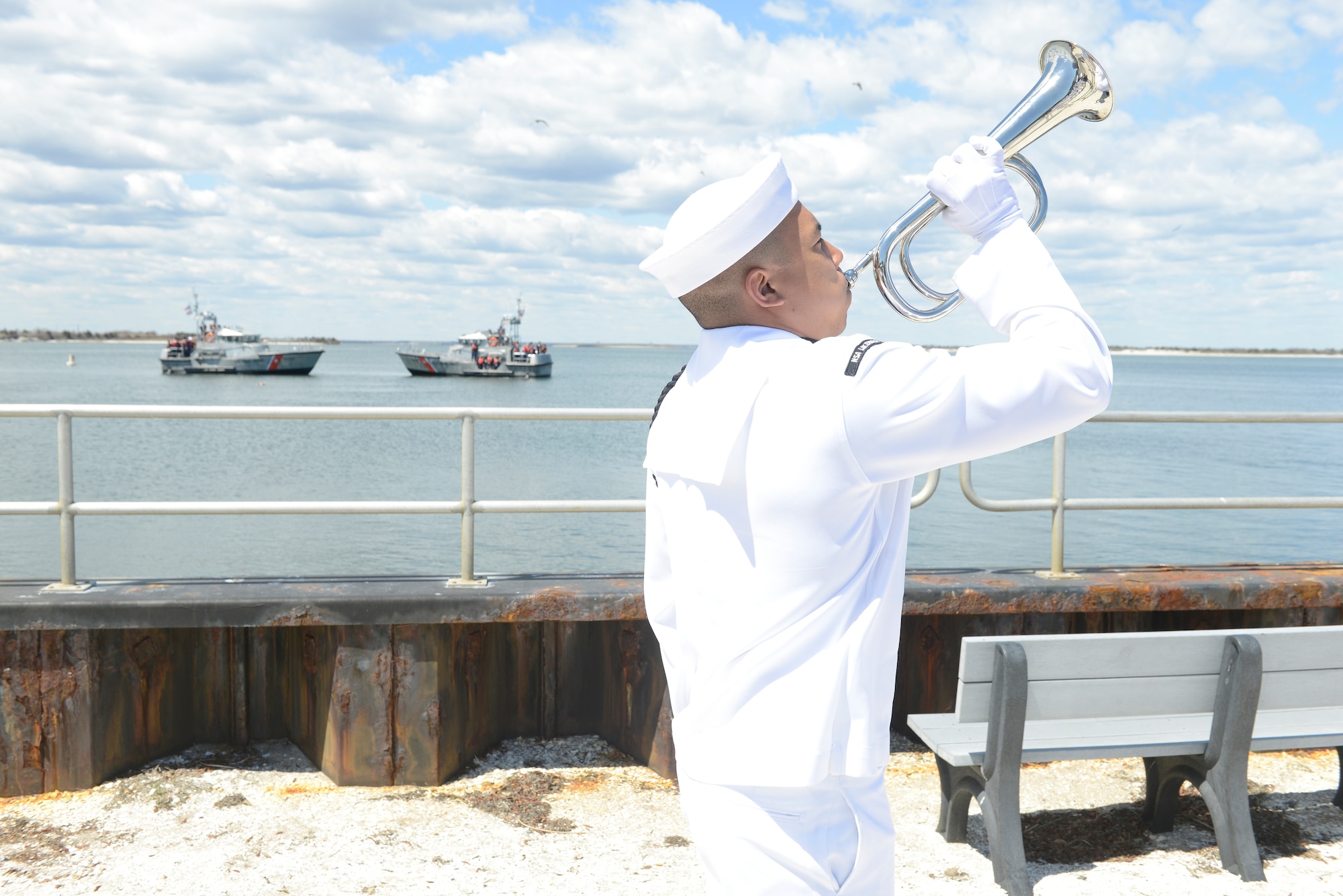 A Navy service member plays taps on a bugle during a wreath laying ceremony at Barnegat Inlet, N.J., Tuesday, April 28, 2015. The wreath was laid to honor the Soldiers and Sailors who lost their lives during the World War II Battle of Exercise Tiger, April 28, 1944. (U.S. Coast Guard photo by Petty Officer 3rd Class David Micallef/Released)
