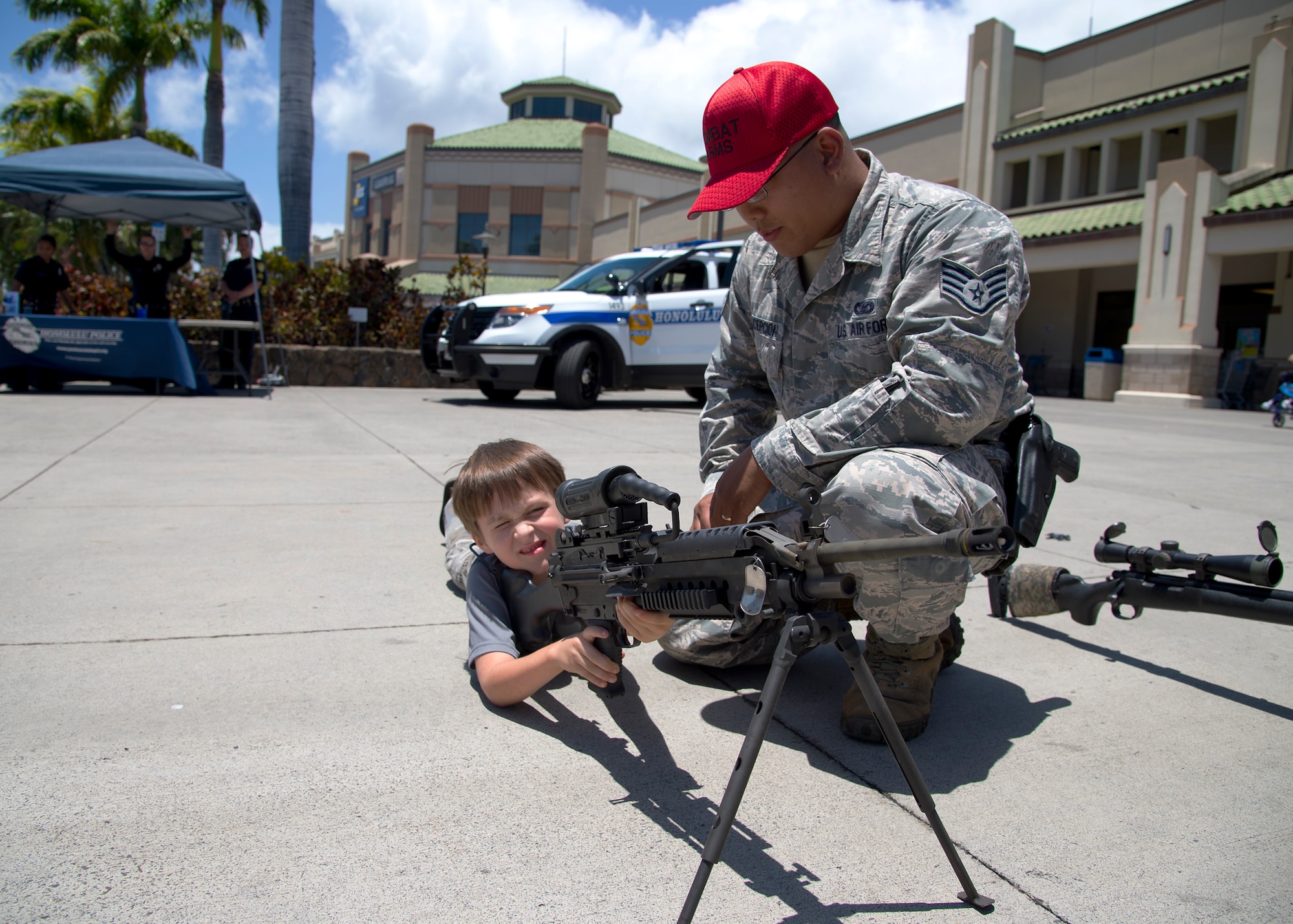 Staff Sgt. Dean Concepcion, 647th Security Forces Squadron combat arms instructor, shows  Hayven the M249 weapon system during  the National Police Week fair at the Navy Exchange Mall, Hawaii, May 13, 2015. In 1962, President John F. Kennedy signed a proclamation which designated May 15 as Peace Officers Memorial Day and the week in which that date falls as Police Week. (U.S. Air Force photo by Tech. Sgt. Aaron Oelrich/Released) 
