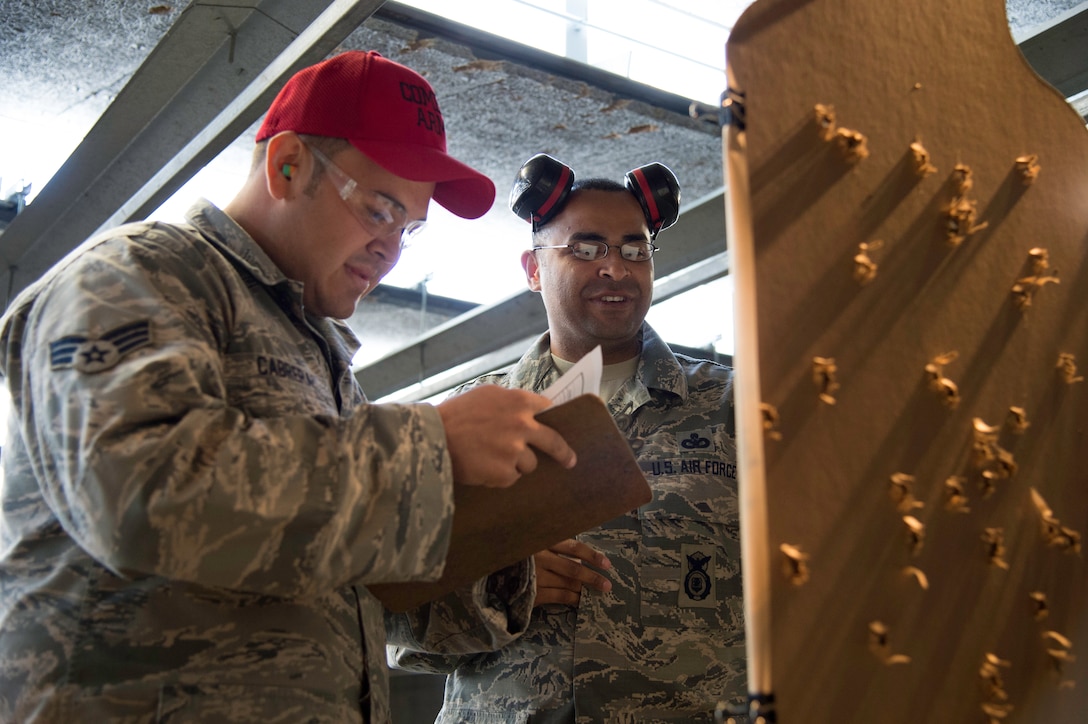 Senior Airman Jorge Cabrera, 11th Security Support Squadron combat arms instructor, left, scores Master Sgt. Julio De Jesus, 11th Security Forces Squadron NCO of police services, target during the Excellence in Competition event at the firing range on Joint Base Andrews, Md., May 14, 2015. This National Police Week event brought together approximately 130 people and marked the first time this competition was held on JBA. (U.S. Air Force photo/Airman 1st Class Philip Bryant)